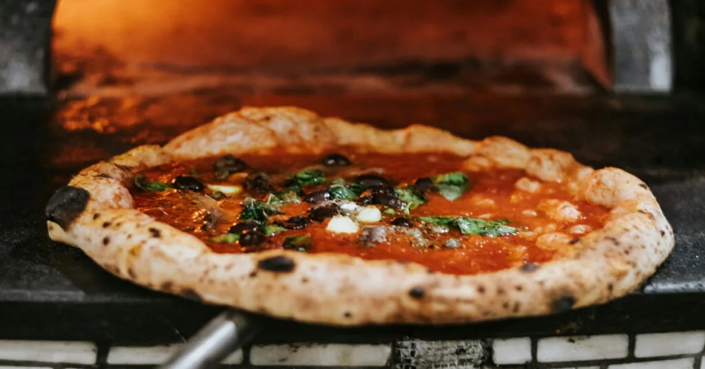 Neapolitan pizza being cooked in a wood-fired oven at Pizzafest in Naples, Italy.